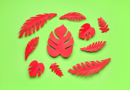 Red paper tropical leaves on green backgroundの写真素材