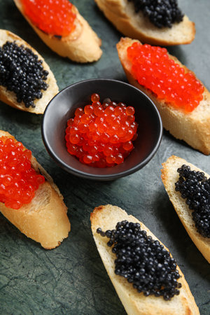 Tasty bruschettas with red and black caviar on color backgroundの写真素材