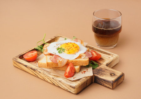 Delicious sandwich with fried egg, tomatoes and bacon on beige backgroundの写真素材