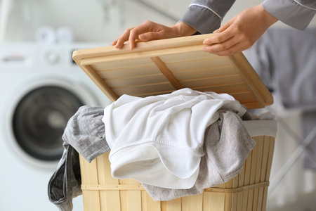 Woman with dirty clothes in laundry basket at home, closeupの写真素材