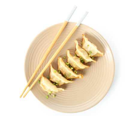Plate with tasty Chinese jiaozi and green onion on white backgroundの写真素材
