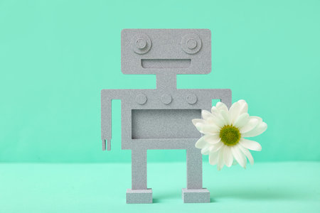 Decorative plaster robot with chamomile flower on turquoise backgroundの写真素材