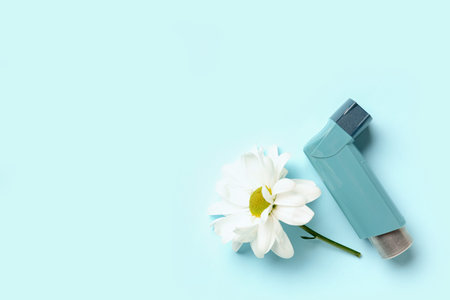 Asthma inhaler with daisy flower on blue background