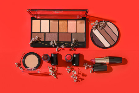Lipsticks with eyeshadows and flowers on red backgroundの写真素材