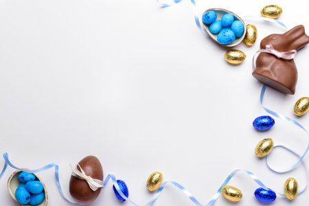 Frame made of chocolate Easter eggs, bunny and ribbon on white backgroundの写真素材