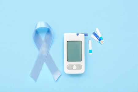 Awareness ribbon with glucometer and strips on blue background. Diabetes conceptの写真素材