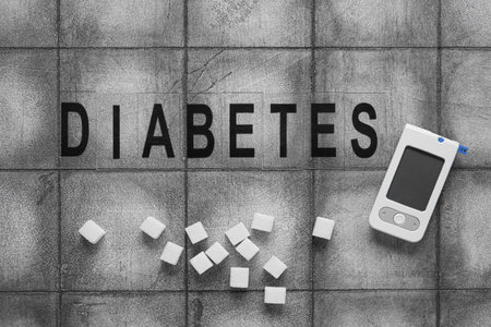 Word DIABETES with glucometer and sugar on dark tile backgroundの写真素材