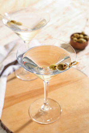 Glasses of tasty martini and olives on light wooden tableの写真素材