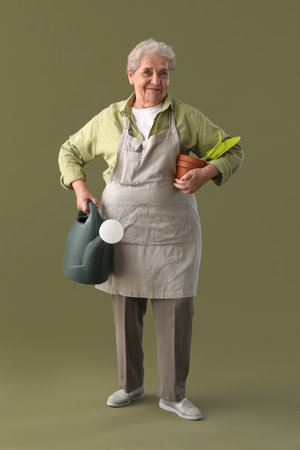 Senior gardener with tools on green backgroundの写真素材