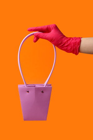 Woman in rubber glove with bag on red backgroundの写真素材