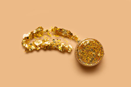 Jar of golden glitter with stroke on beige backgroundの写真素材