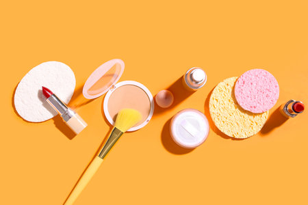 Decorative cosmetics with makeup brush and sponges on color backgroundの写真素材