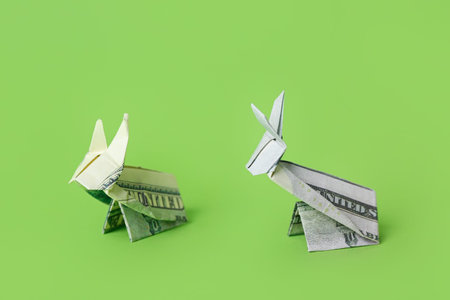 Origami rabbits made of dollar banknotes on green backgroundの写真素材