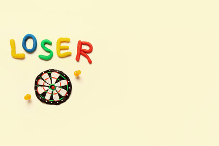 Word LOSER with dartboard made of plastic and pins on white background