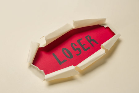 Word LOSER visible through hole in white paper, closeupの写真素材