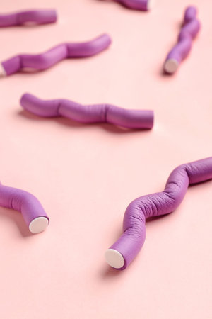 Hair curlers on pink background, closeup