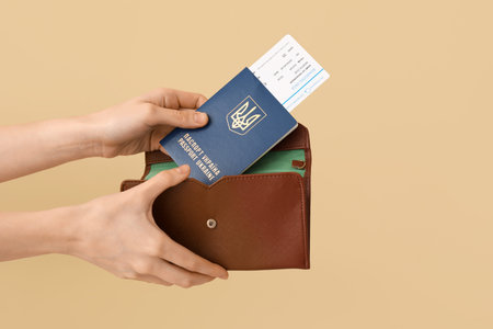 Woman Ukrainian passport with ticket in wallet putting on beige background