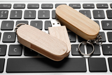 Wooden USB flash drives on modern laptop, closeup