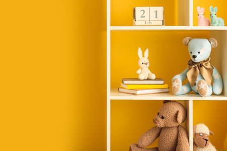 Bookshelf with baby toys near yellow wallの写真素材