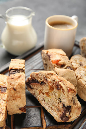 Board with delicious biscotti cookies and cup of coffee on gray grunge backgroundの写真素材