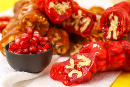 Delicious churchkhela and bowl with pomegranate on yellow backgroundの写真素材