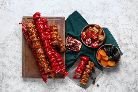 Board with delicious churchkhela, pomegranate, dried apricot and prunes on white grunge backgroundの写真素材