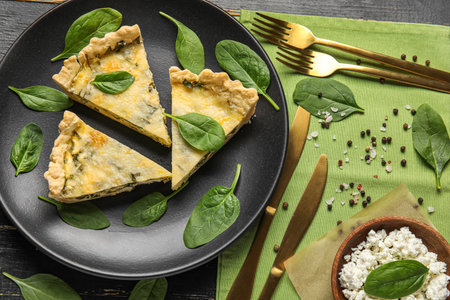 Plate with pieces of delicious quiche on black wooden backgroundの写真素材