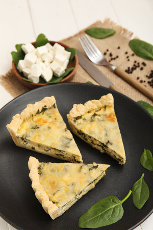 Plate with pieces of delicious quiche and feta cheese on white wooden backgroundの写真素材