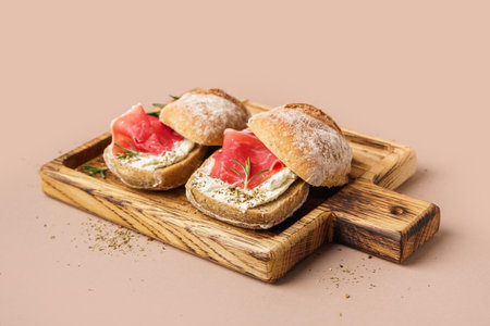 Wooden board of tasty sandwiches with jamon on beige backgroundの写真素材