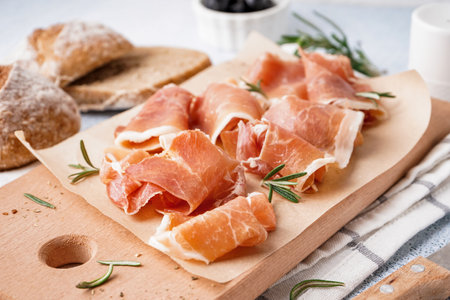 Wooden board with slices of tasty jamon on table, closeupの写真素材