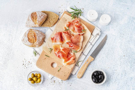 Wooden board with slices of tasty jamon on light backgroundの写真素材