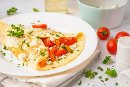 Tasty omelet with tomatoes and parsley on light tableの写真素材
