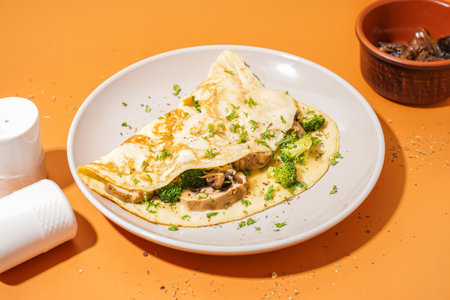 Tasty omelet with broccoli and mushrooms on orange backgroundの写真素材