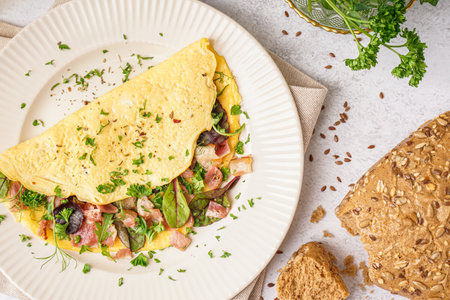 Tasty omelet with ham and greens on light tableの写真素材