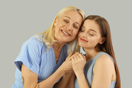 Young woman with her mother on gray background, closeup