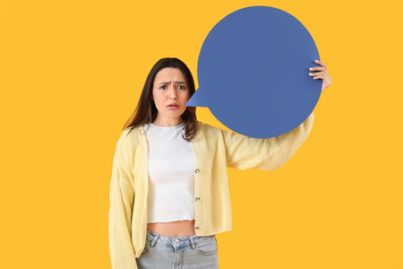 Sad young woman with blank speech bubble on yellow backgroundの写真素材