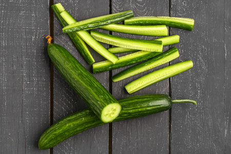 Fresh cut cucumbers on dark wooden backgroundの写真素材