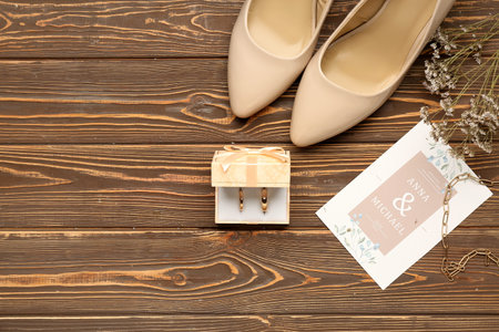 Box with wedding rings, invitation, flowers and heels on wooden background