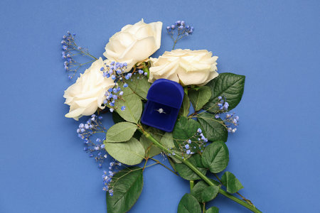 Box with engagement ring and flowers on blue backgroundの写真素材