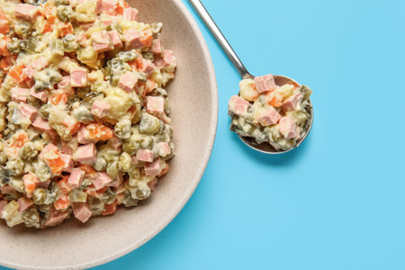 Bowl of tasty Olivier salad on blue background, closeupの写真素材