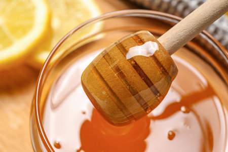 Jar of sweet honey with dipper on table, closeupの写真素材