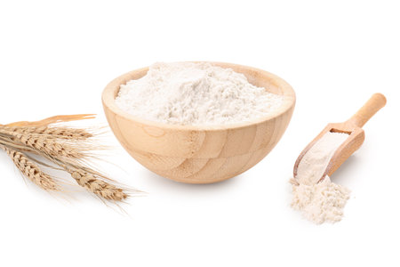 Wooden bowl with flour, scoop and wheat ears isolated on white backgroundの写真素材