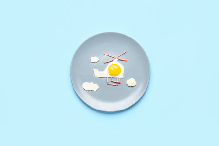 Plate with funny children's breakfast in shape of helicopter on blue backgroundの写真素材