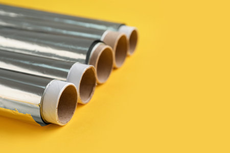Aluminum foil rolls on yellow background, closeupの写真素材
