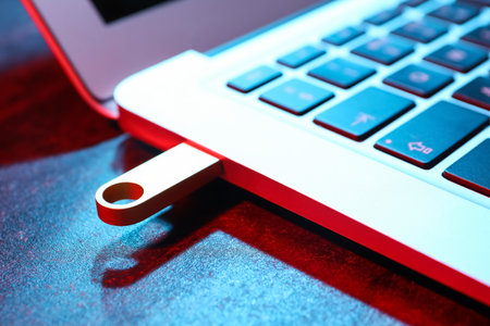 Modern laptop with metallic USB flash drive on black table, closeupの写真素材