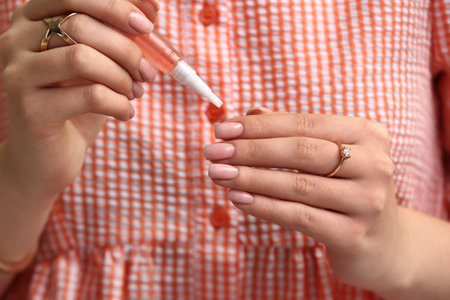Woman with cuticle oil pen, closeupの写真素材