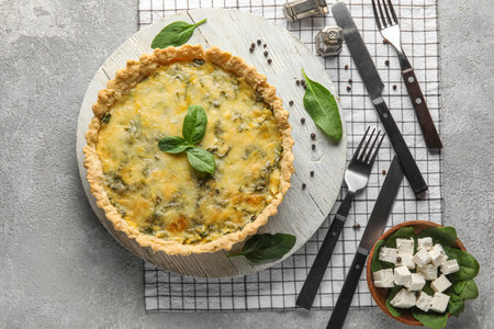 Board with delicious quiche and cutlery on gray grunge backgroundの写真素材