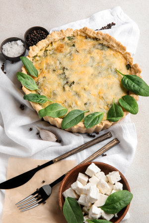 Napkin with delicious quiche, spinach leaves and bowl of feta cheese on gray backgroundの写真素材