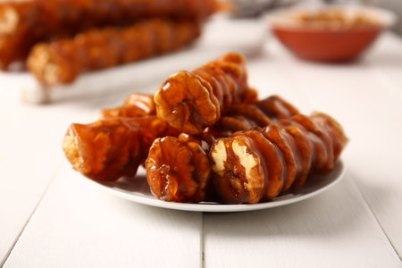Plate with tasty churchkhela on light wooden background