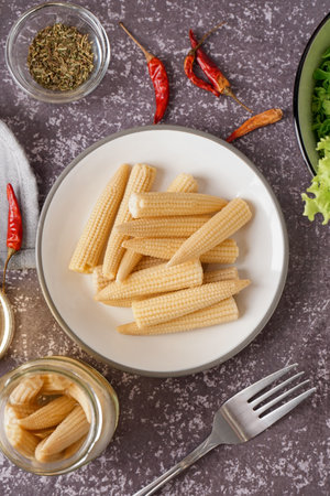 Plate with canned baby corn cobs on gray grunge backgroundの写真素材